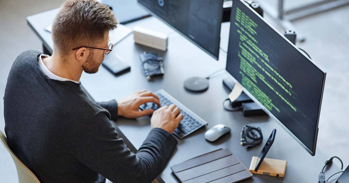 Software ontwikkelaar schrijft code zittend achter een computer en data systeem