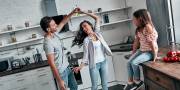 Dansend stel in keuken terwijl kind toekijkt zittend op aanrecht 